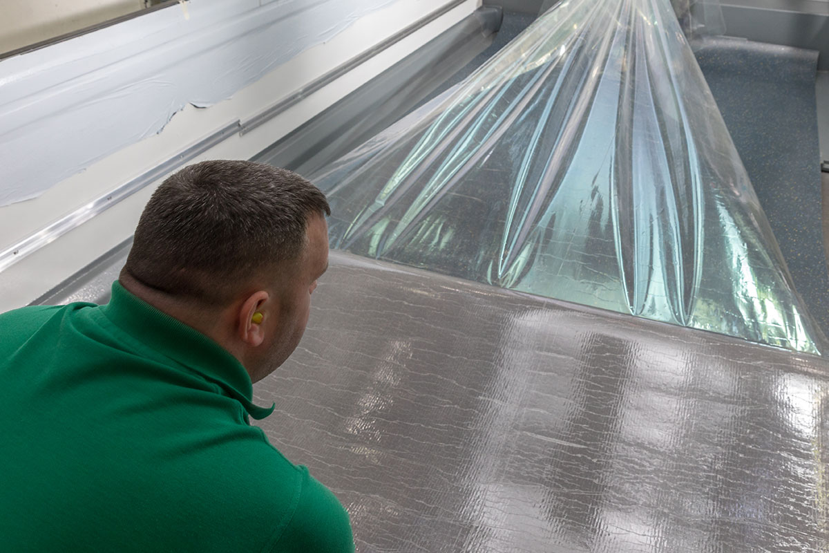 A floor fitter pulling the protective film off of some self-adhesive flooring