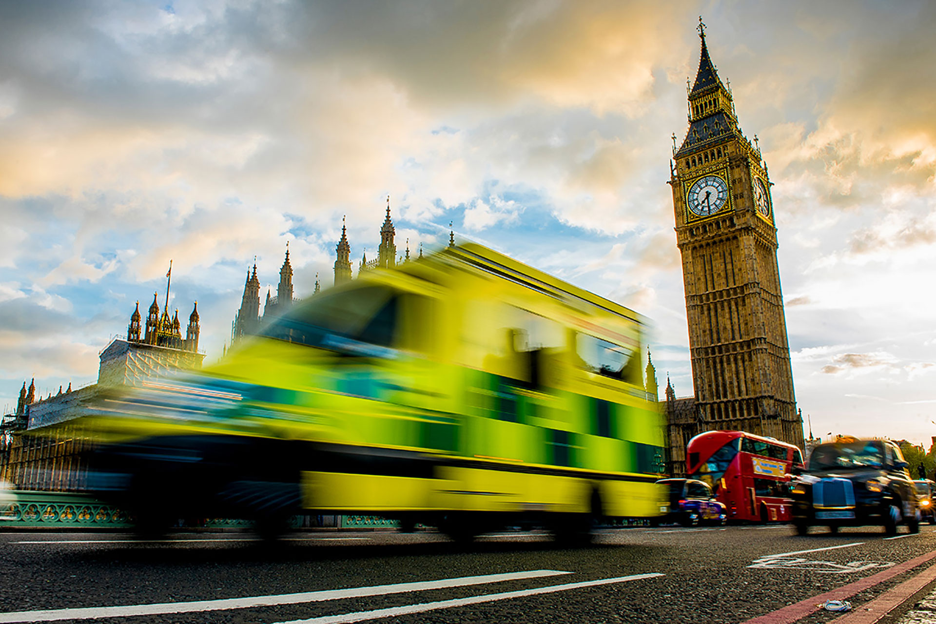 A British ambulance travelling over Westminster Bridge with Big Ben in the background.