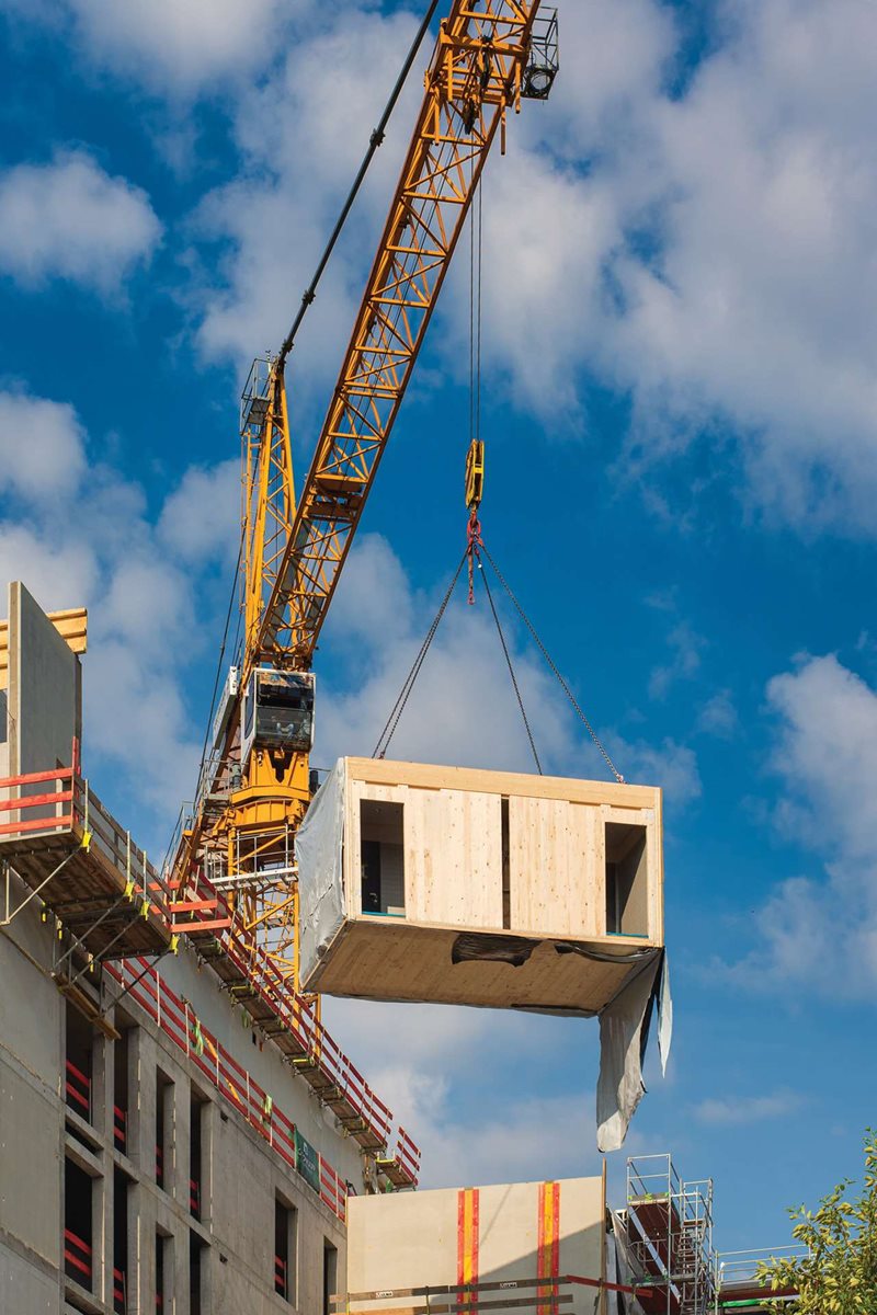 Crane hoisting modular building into place
